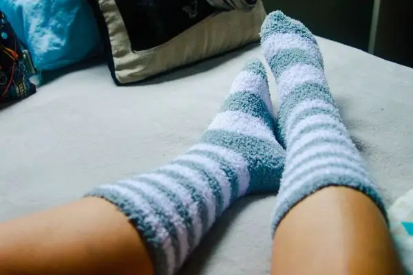 Como Prevenir E Cuidar Do Ressecamento Dos Pés No Dia A Dia 2 pés relaxando com meias ou envoltos em toalhas, demonstrando cuidado e conforto